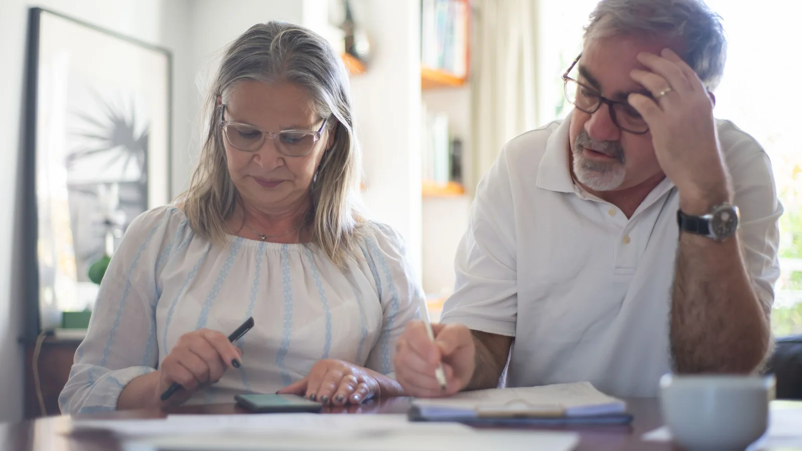 Un couple de seniors relit des documents pour rechercher un contrat d’assurance dépendance oublié