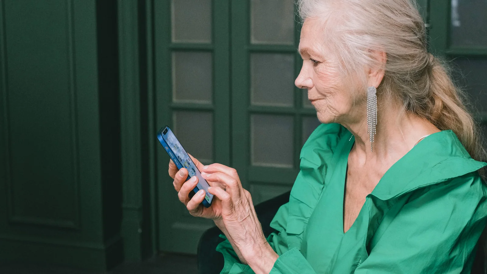 Une femme retraitée consulte attentivement une information sur son smartphone