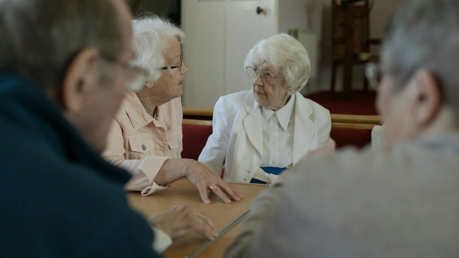 Des personnes âgées échangent autour d’une table lors d’une réunion collective