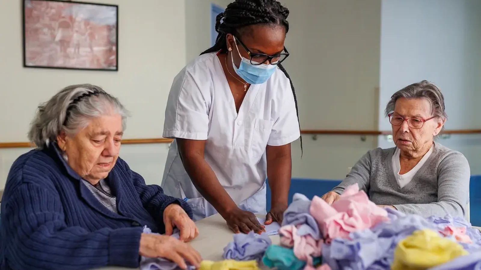 Une aide-soignante accompagne 2 résidentes lors d’une activité dans un EHPAD