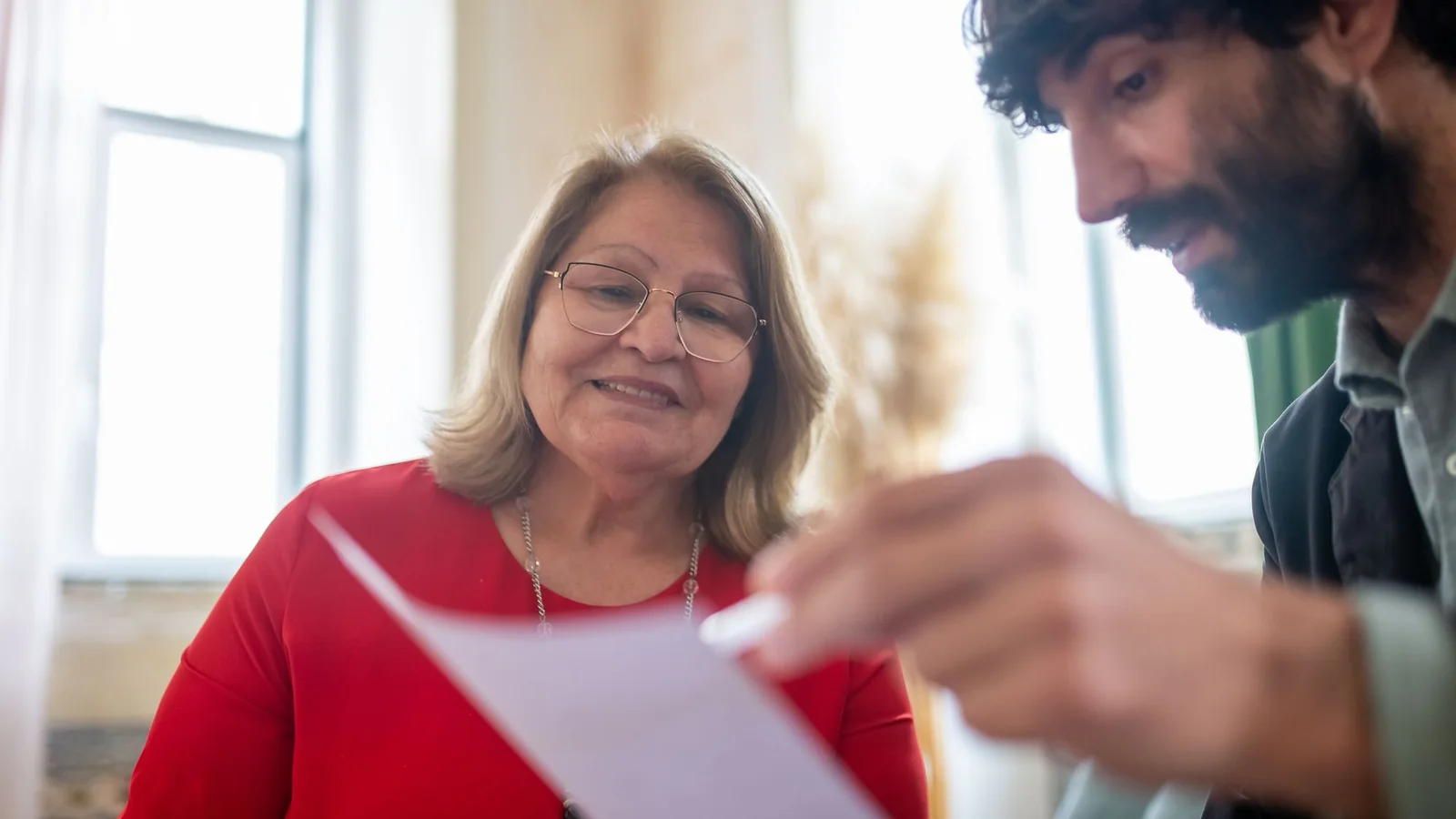 Une femme âgée examine un dossier avec un homme qui lui présente des documents d’aide financière