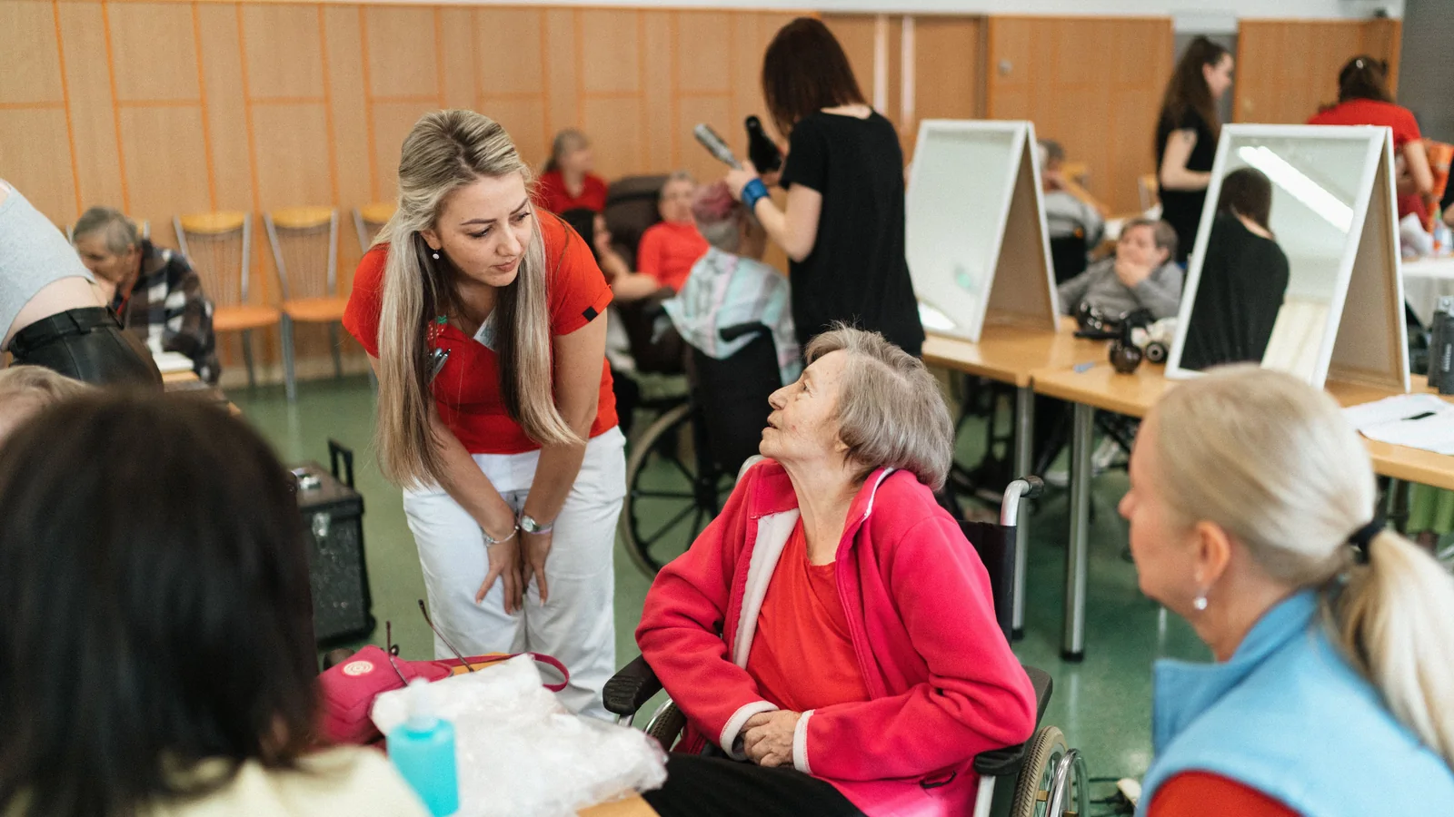Une professionnelle échange avec une femme âgée installée dans un fauteuil roulant