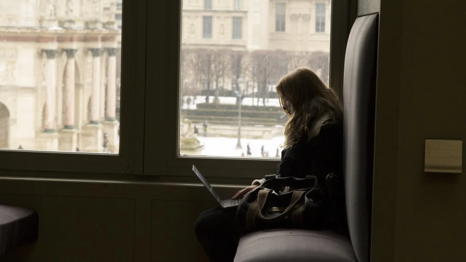 Une voyageuse utilise un ordinateur portable devant les fenêtres du musée du Louvre à Paris