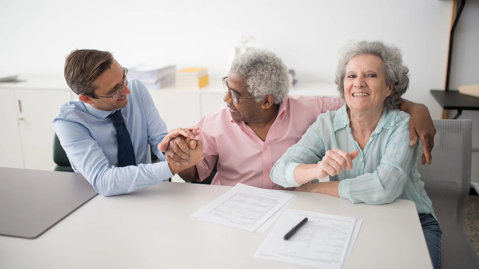 Un couple de seniors échange avec un conseiller devant des documents financiers