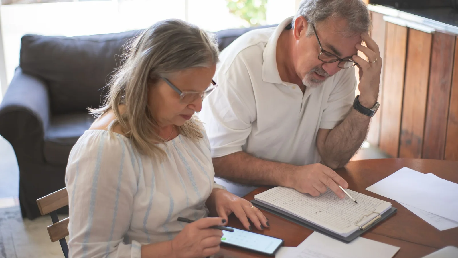 Un couple de seniors consulte des documents et un smartphone à une table