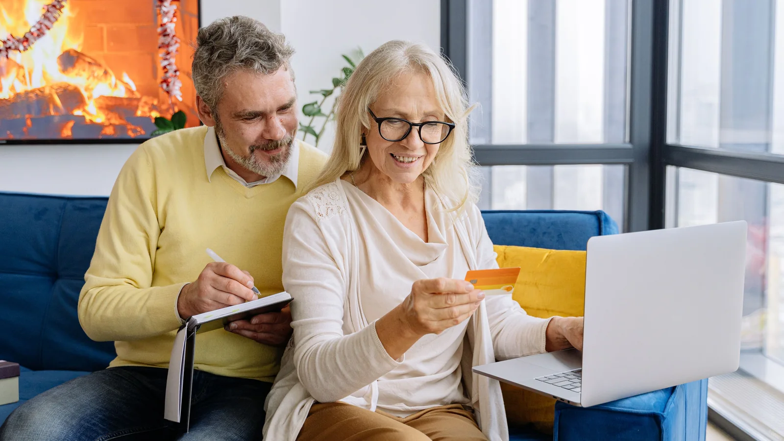 Un couple de retraités consulte un compte en ligne et une carte bancaire devant un ordinateur portable