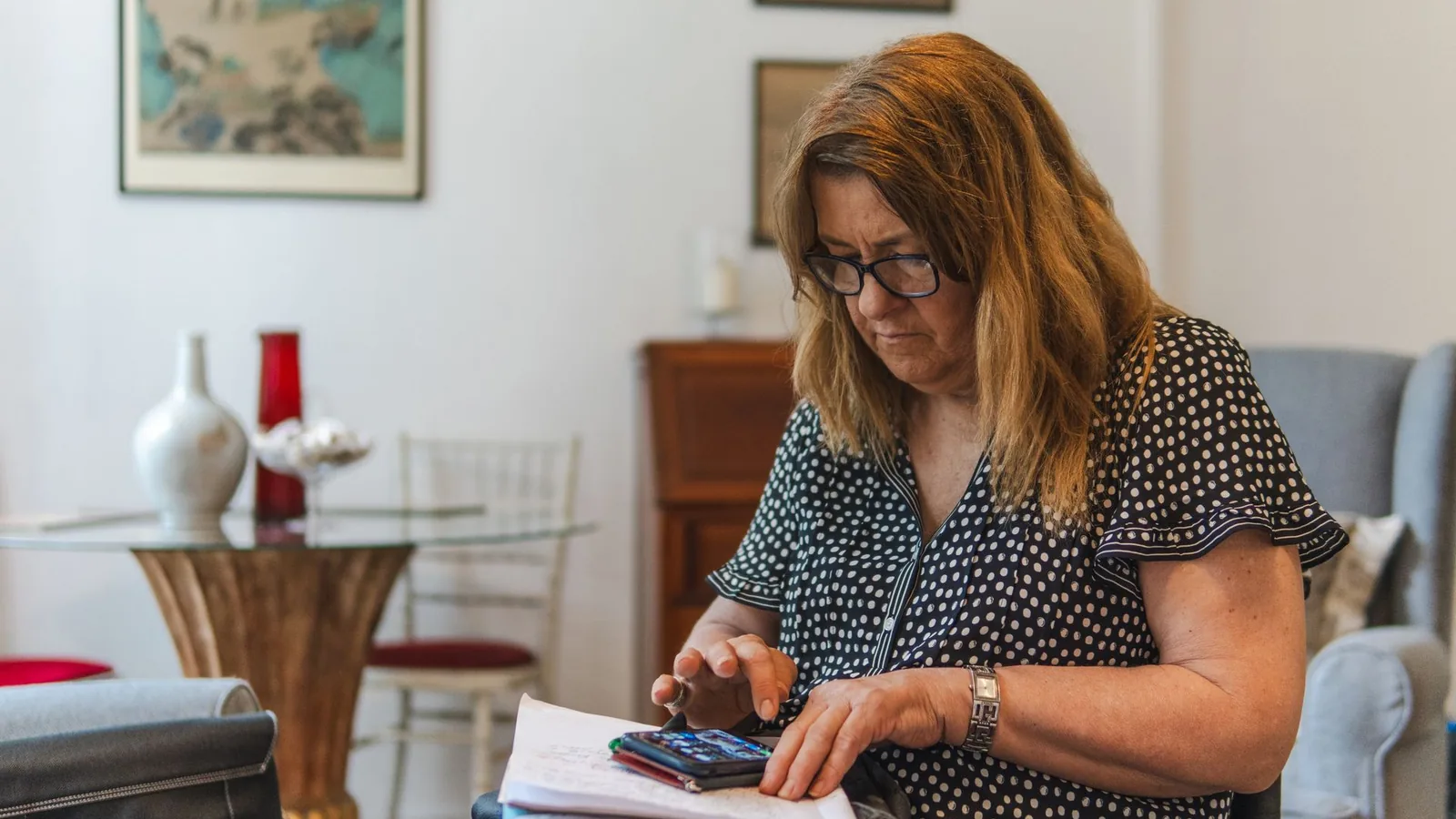 Une femme consulte ses factures et utilise une calculatrice pour vérifier son budget énergie