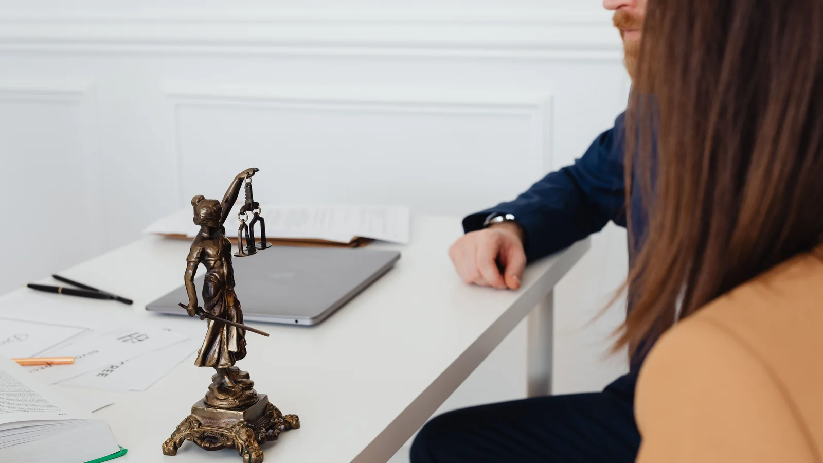 Une statuette de la Justice devant un couple réuni dans un cabinet juridique