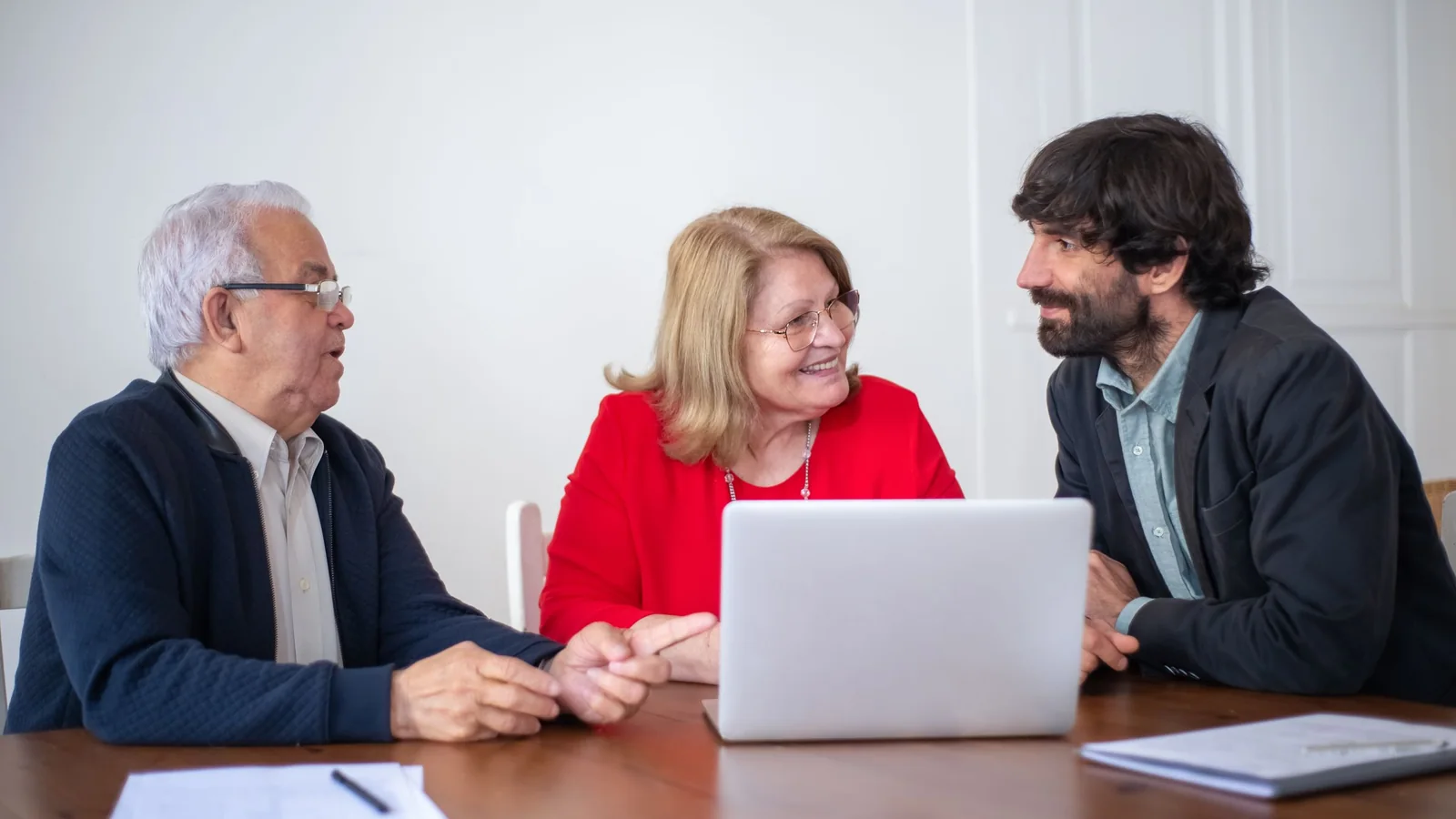 Couple âgé échangeant avec un conseiller devant un ordinateur et des documents