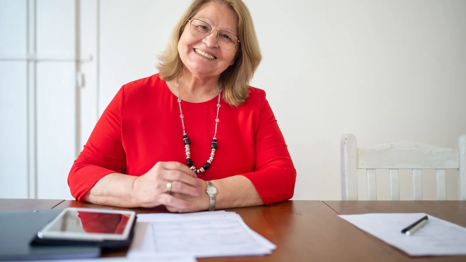 Une femme senior assise à une table devant des documents liés à la préparation de son patrimoine