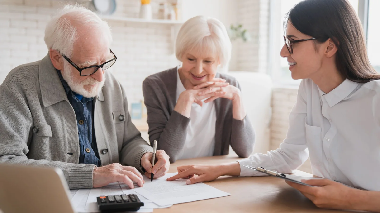 Un couple de seniors examine et signe des documents avec une conseillère