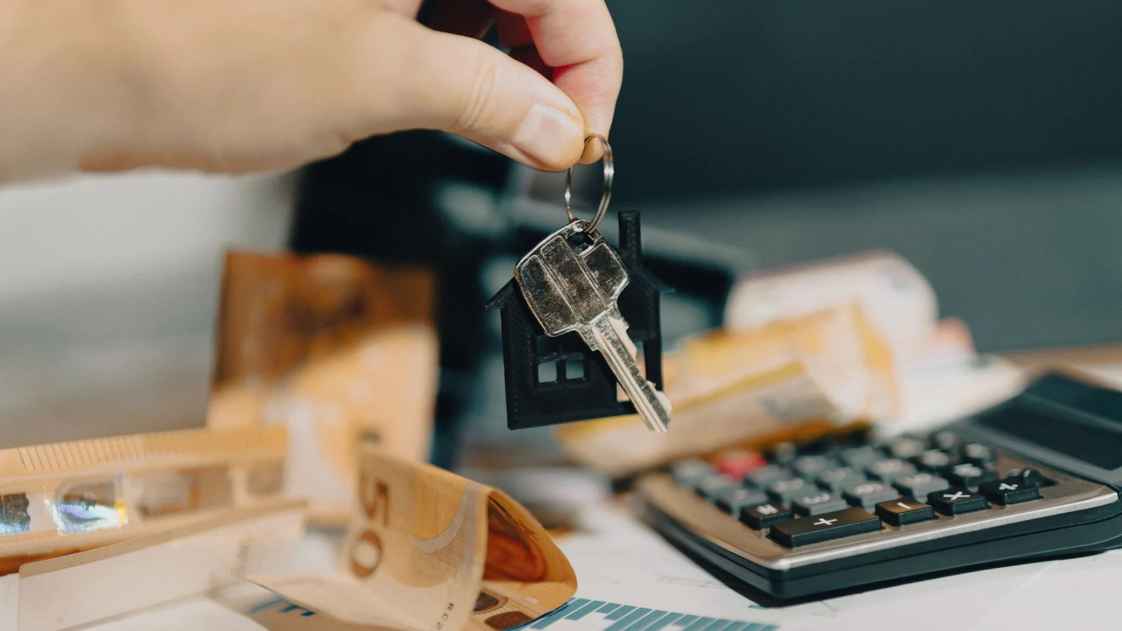 Des clés de logement au-dessus de billets en euros et d’une calculatrice pour illustrer la valeur d’un appartement hérité