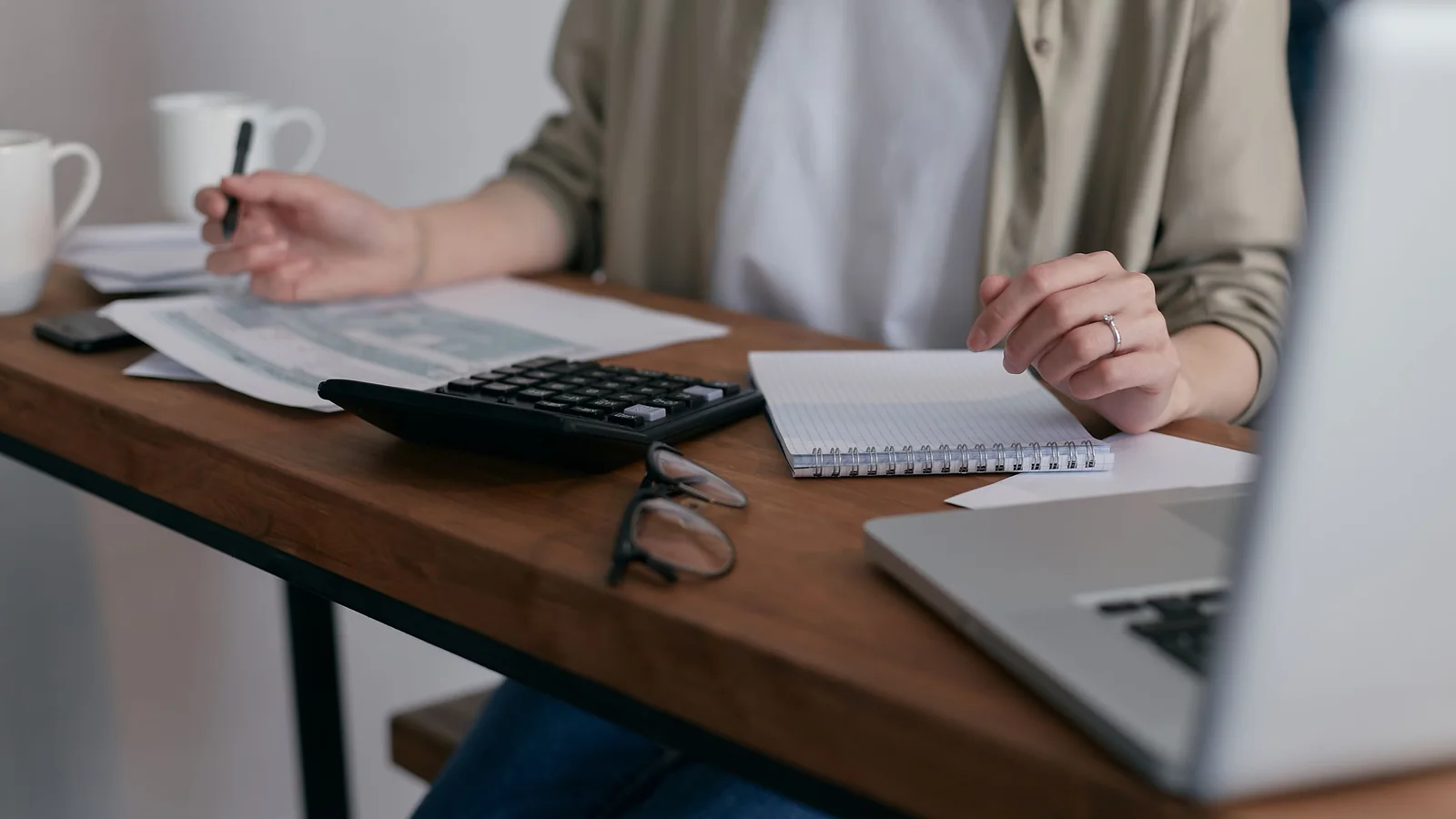 Une femme calcule son budget devant des factures et une calculatrice sur une table