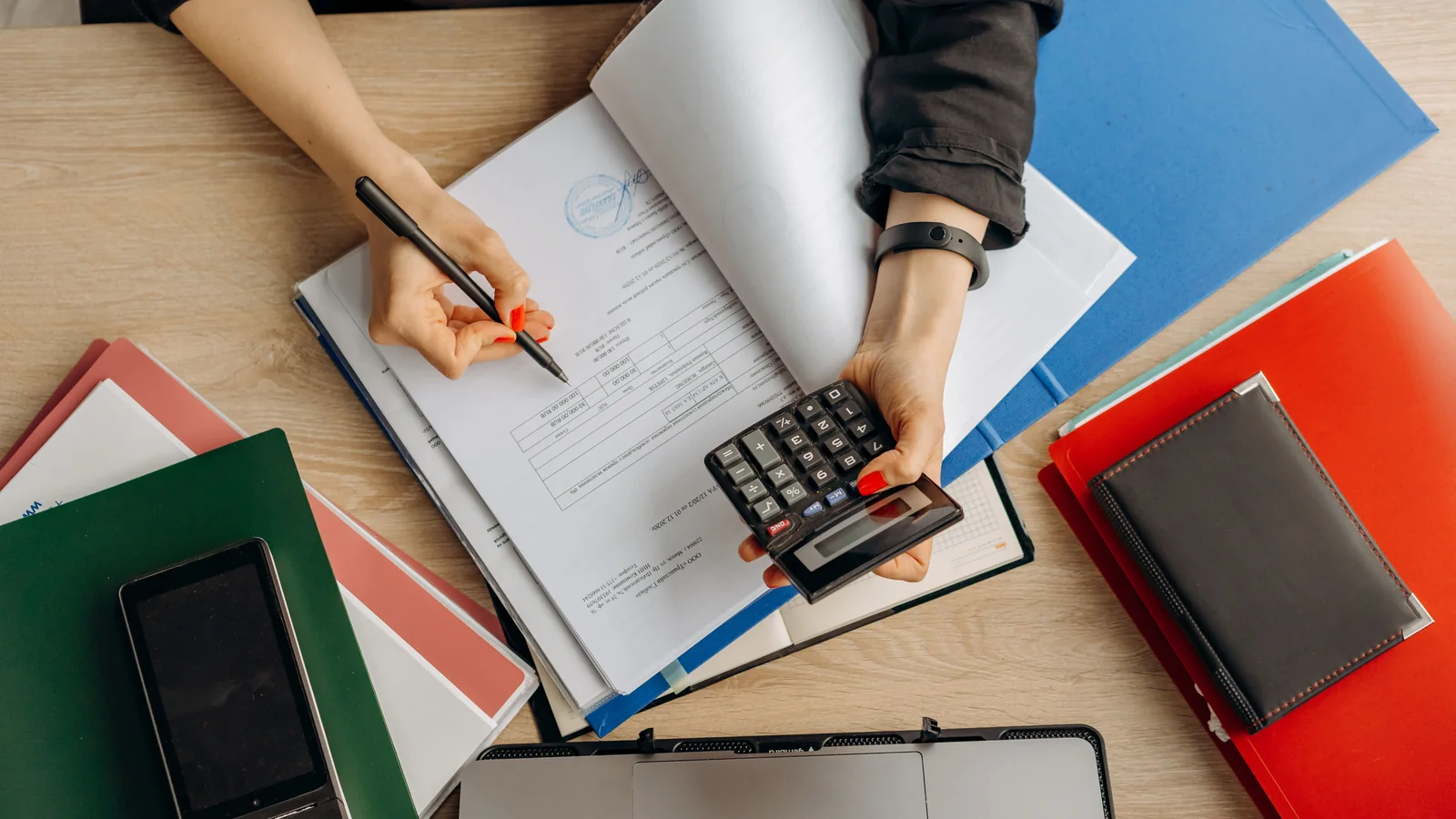 Une professionnelle vérifie des documents financiers avec une calculatrice