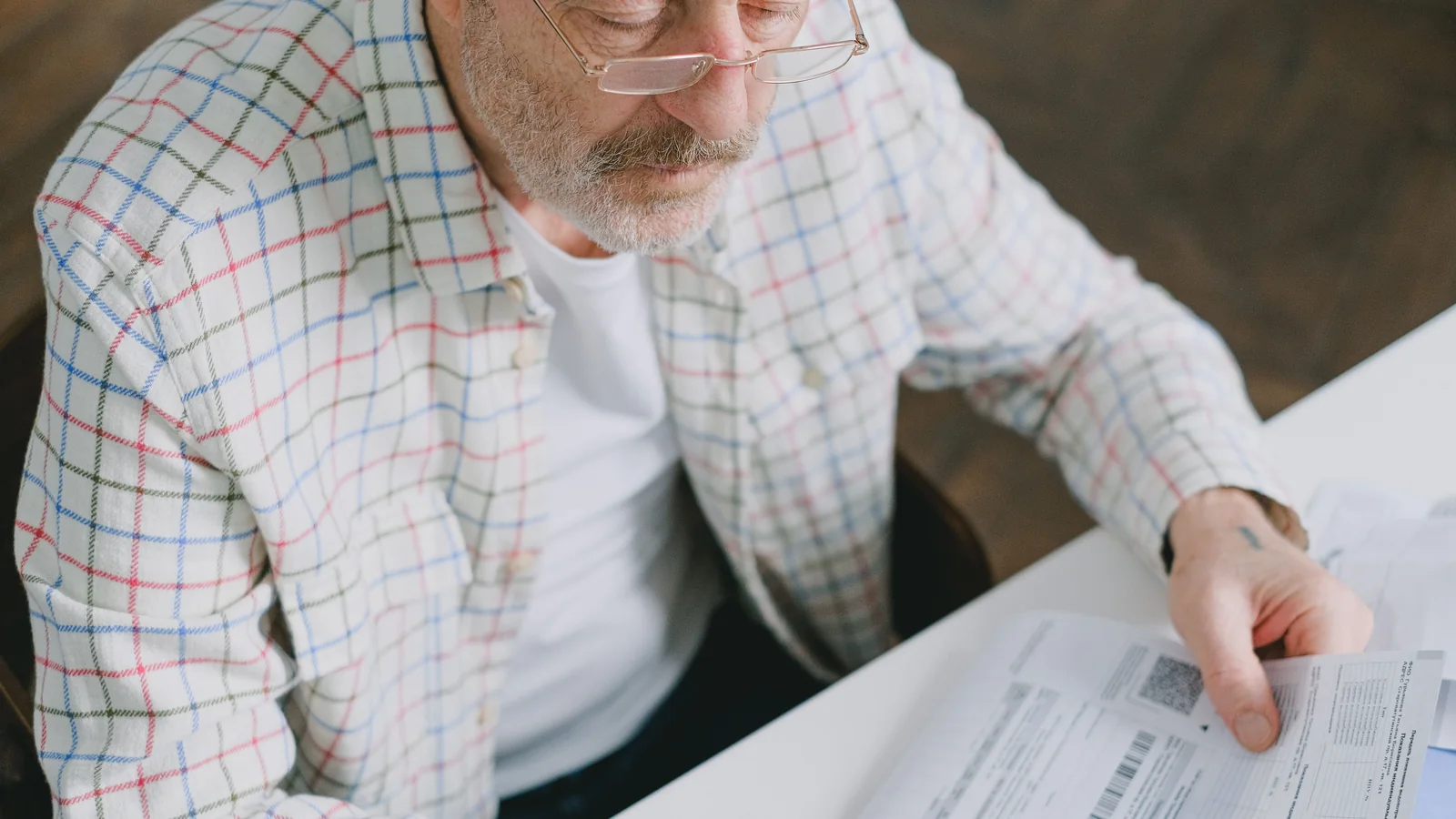 Un homme âgé examine attentivement des documents à son domicile