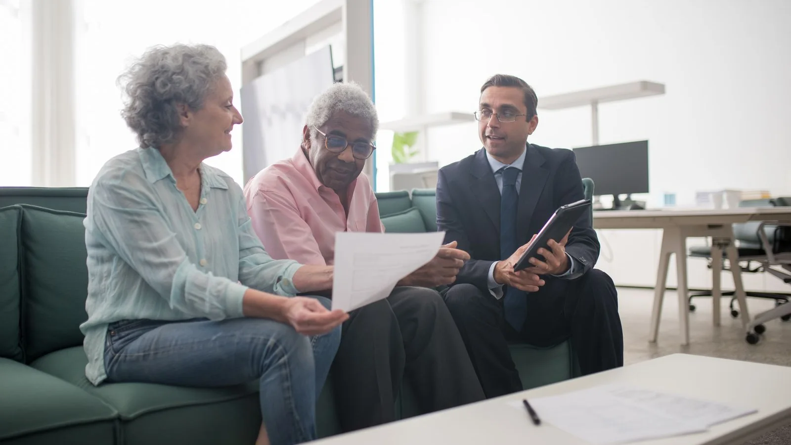 Un couple de seniors examine des documents avec un conseiller dans un bureau