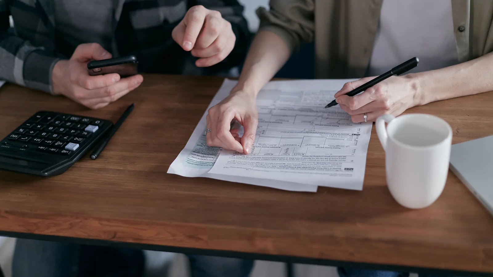 Un couple examine des documents financiers avec une calculatrice et un smartphone