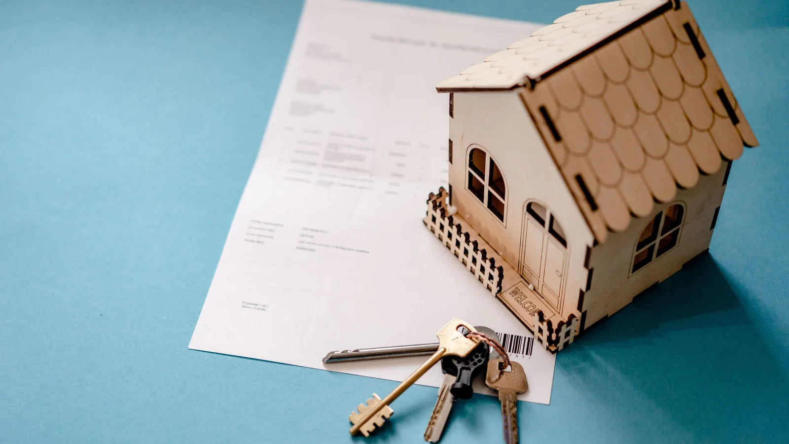 Maquette de maison posée sur un contrat immobilier avec un trousseau de clés