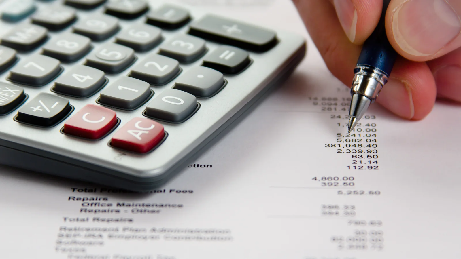 Main utilisant une calculatrice sur un relevé financier pour mesurer l’effet de nouvelles règles fiscales