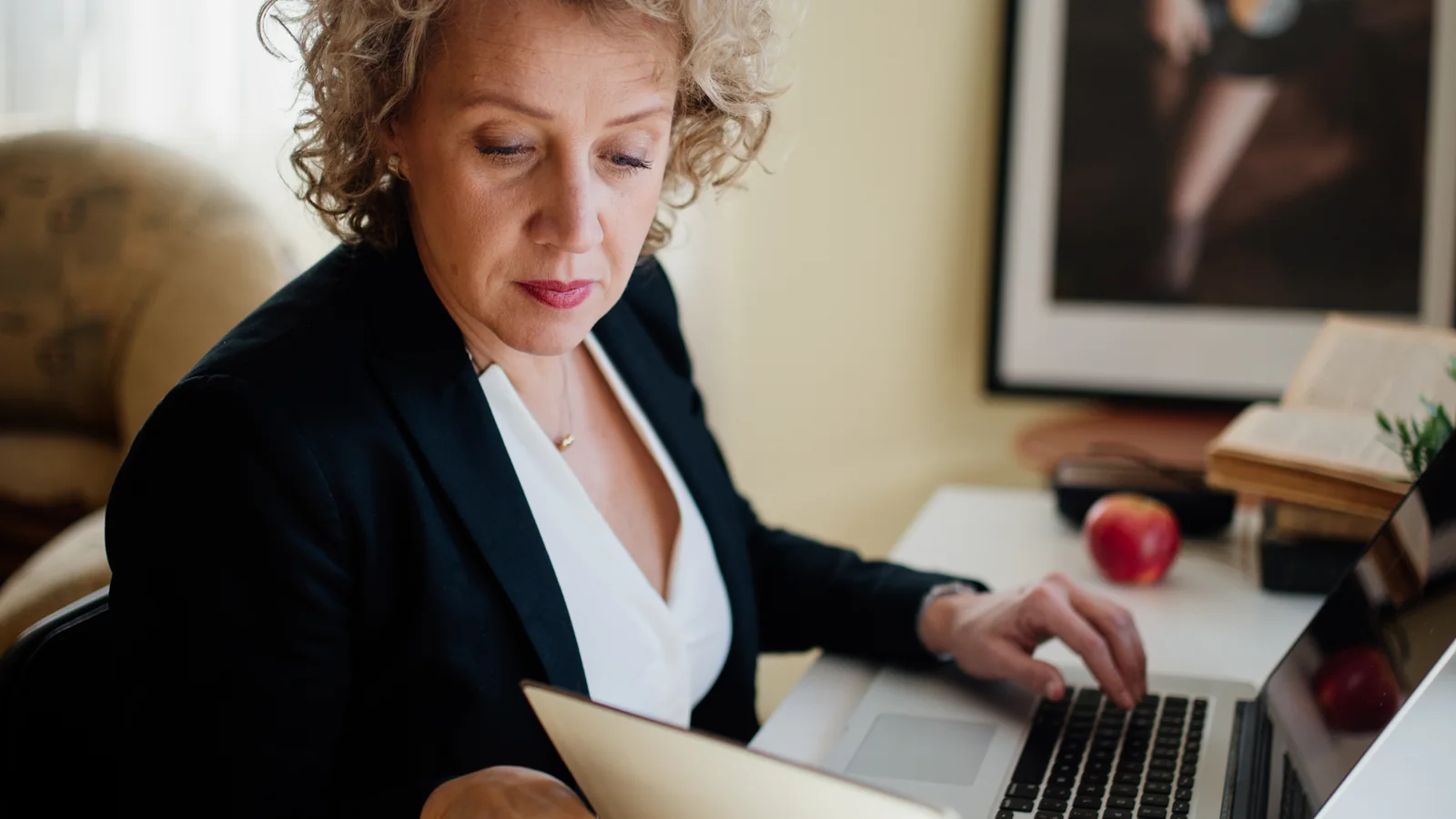 Une salariée examine des documents devant son ordinateur portable pour vérifier des retenues sur sa paie