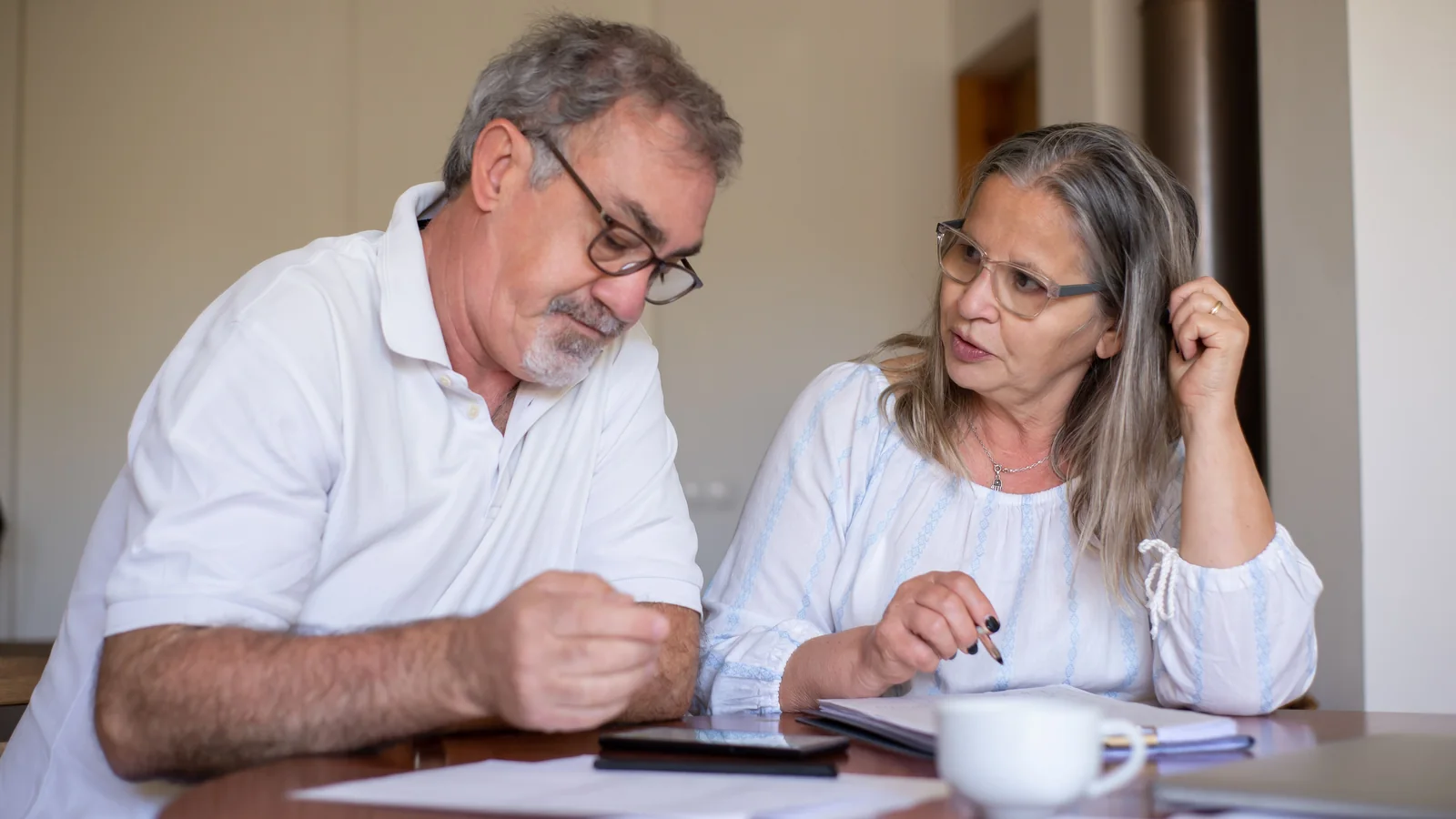 Un couple de retraités examine ensemble des documents et des dépenses sur une table