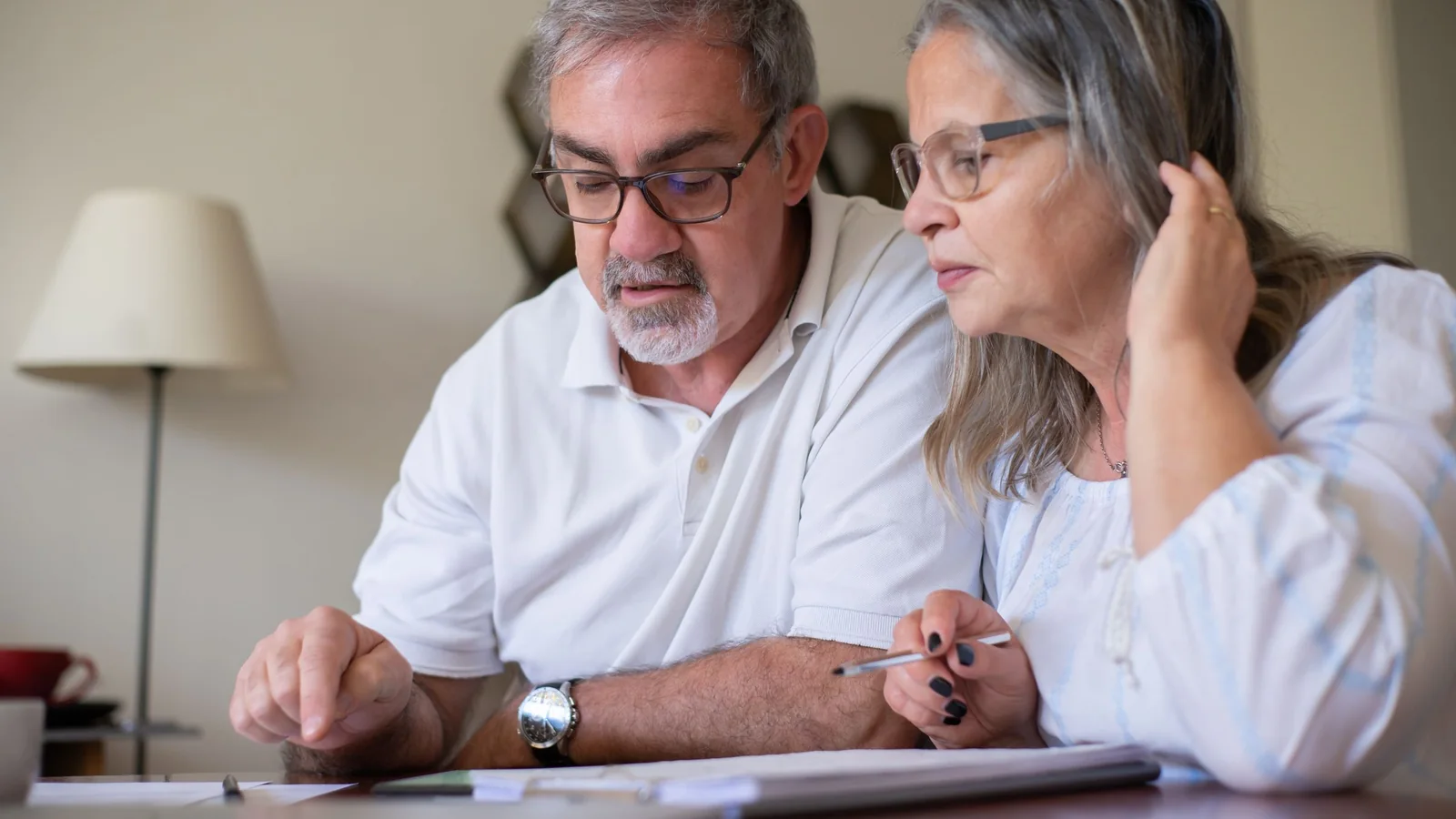 Un couple de seniors examine des documents de transmission familiale autour d’une table