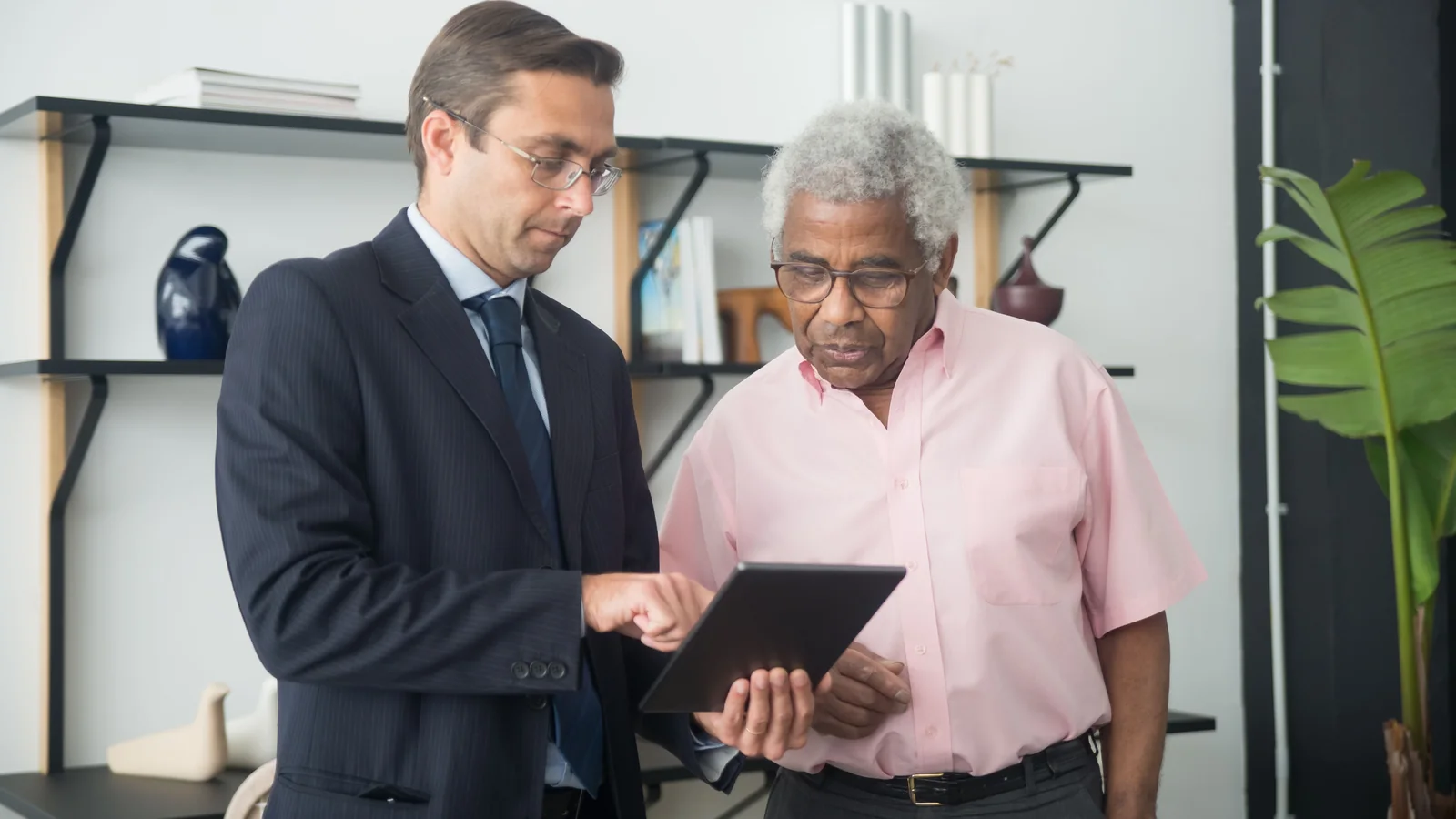 Un retraité consulte des démarches administratives sur une tablette avec un conseiller
