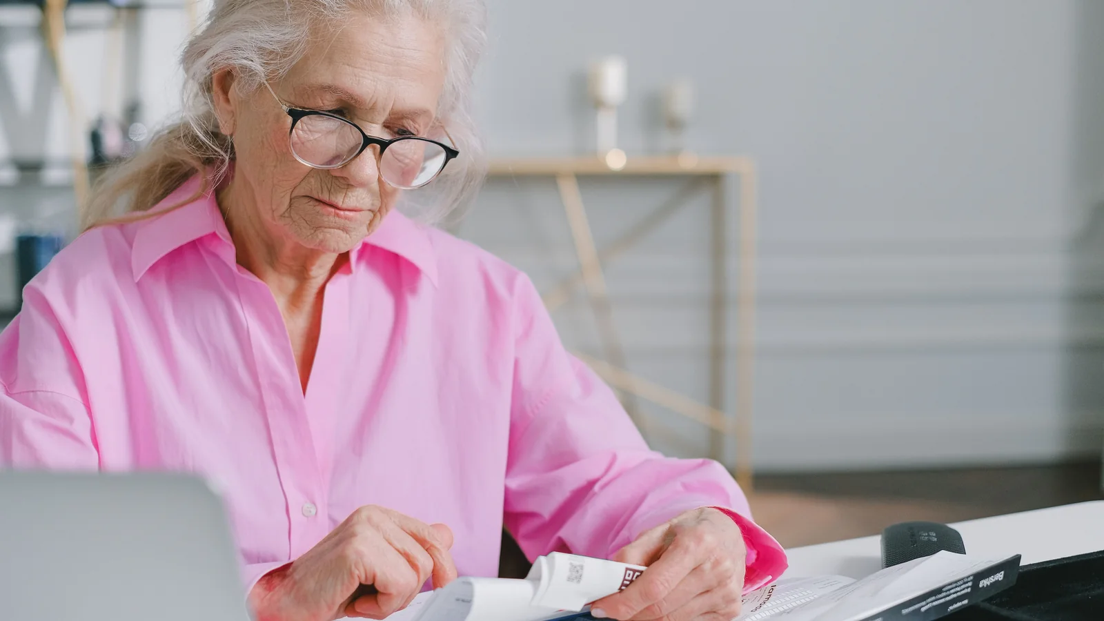 Une femme âgée préoccupée consulte des documents concernant sa pension de réversion