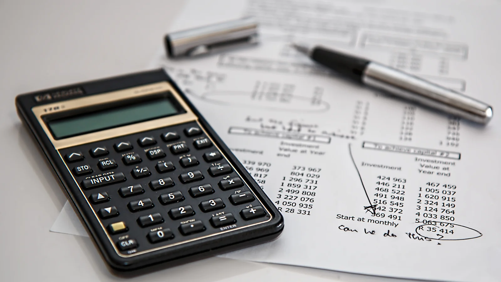 Calculatrice posée sur des relevés chiffrés pour comparer une épargne PER et assurance-vie