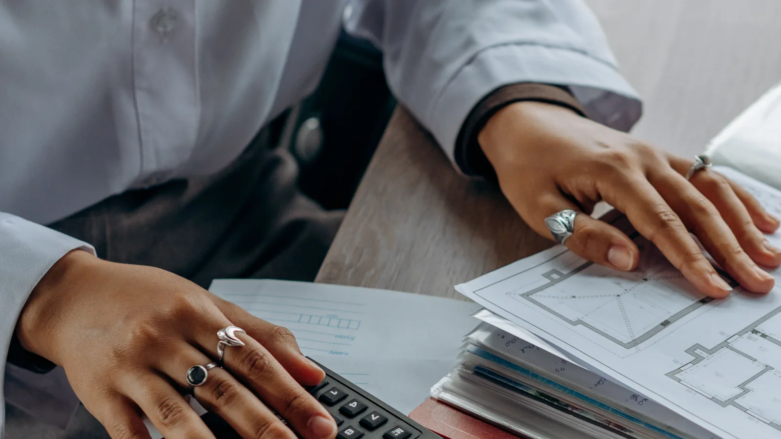 Une professionnelle utilise une calculatrice au-dessus de documents de travail