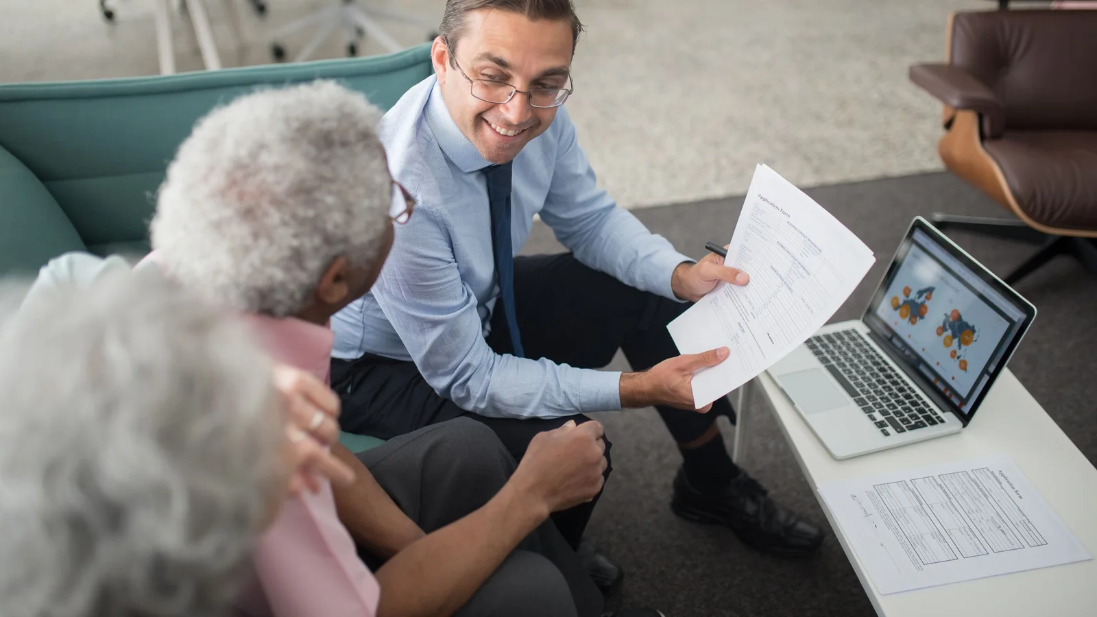 Un conseiller présente des documents financiers à un couple de seniors lors d’un rendez-vous