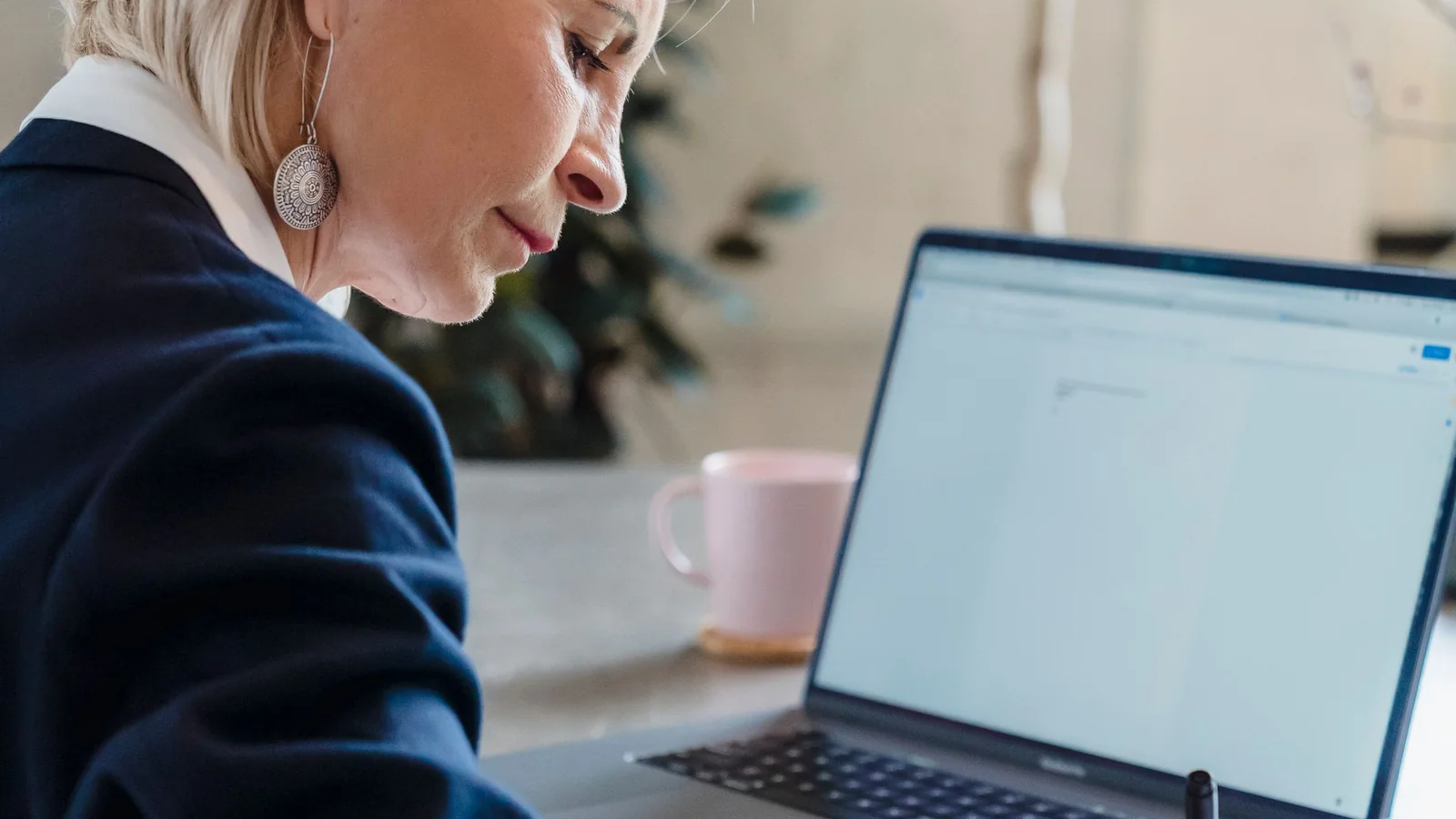 Une femme senior travaille devant un ordinateur portable et des documents