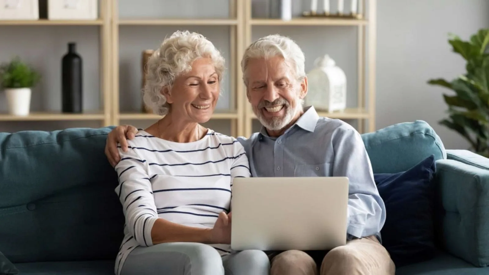 Un couple de retraités consulte un ordinateur portable sur un canapé