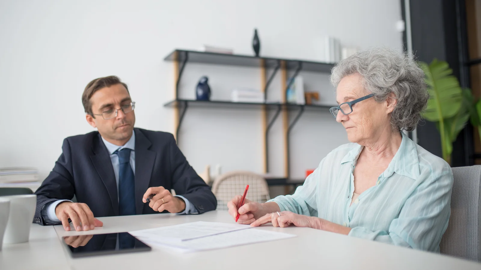 Une salariée senior examine des documents avec un conseiller avant de signer