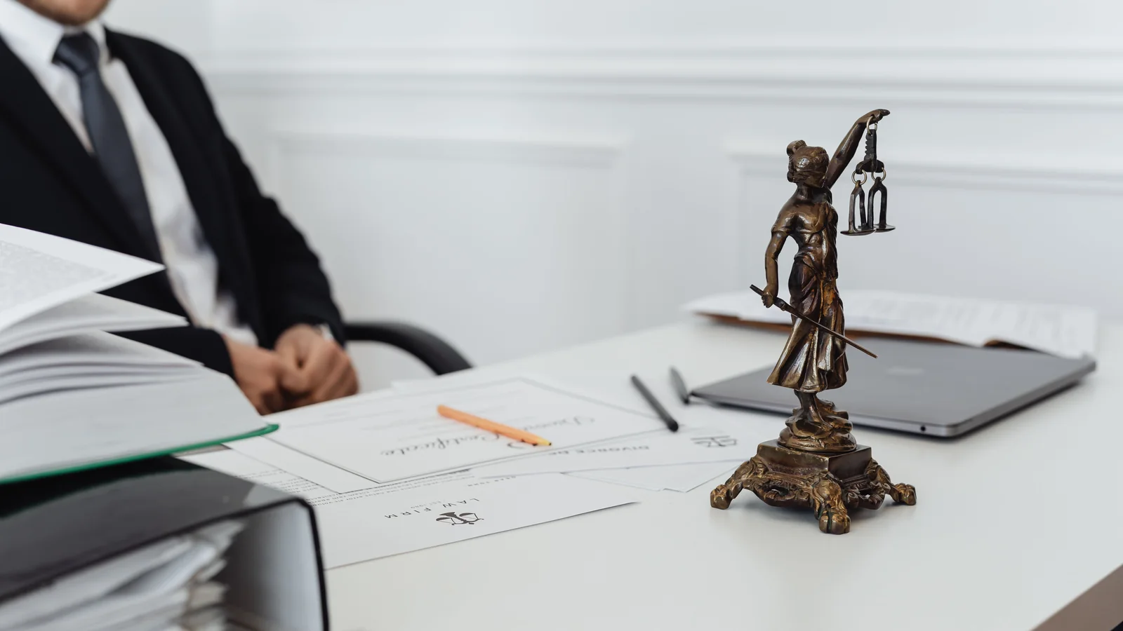 Une statuette de la Justice devant des dossiers juridiques examinés sur un bureau