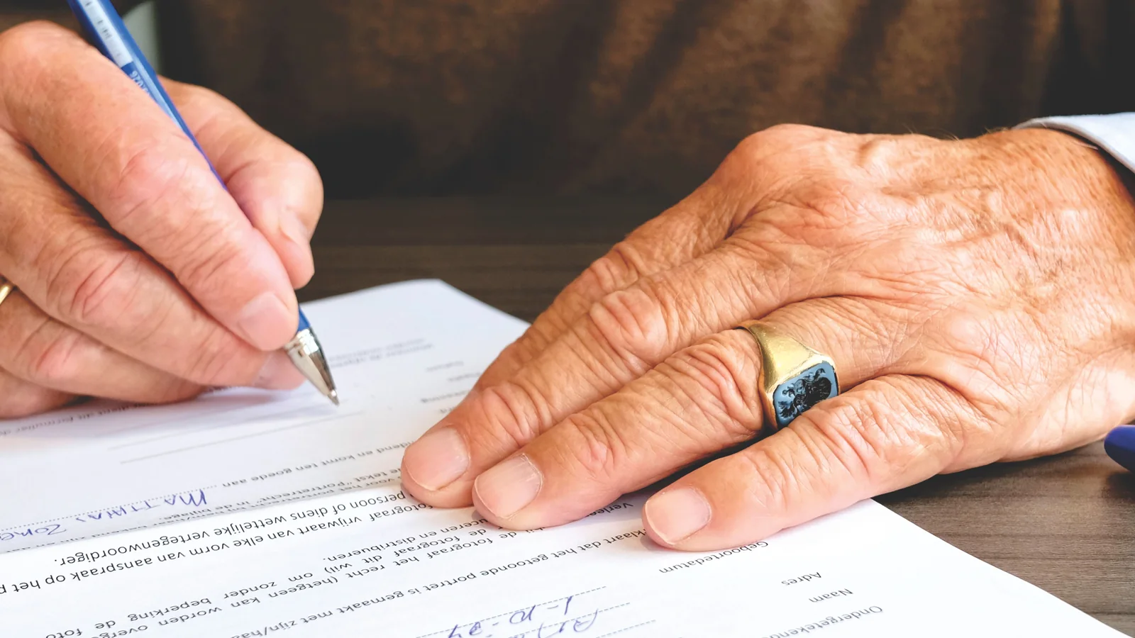 Des mains signent un document posé sur une table