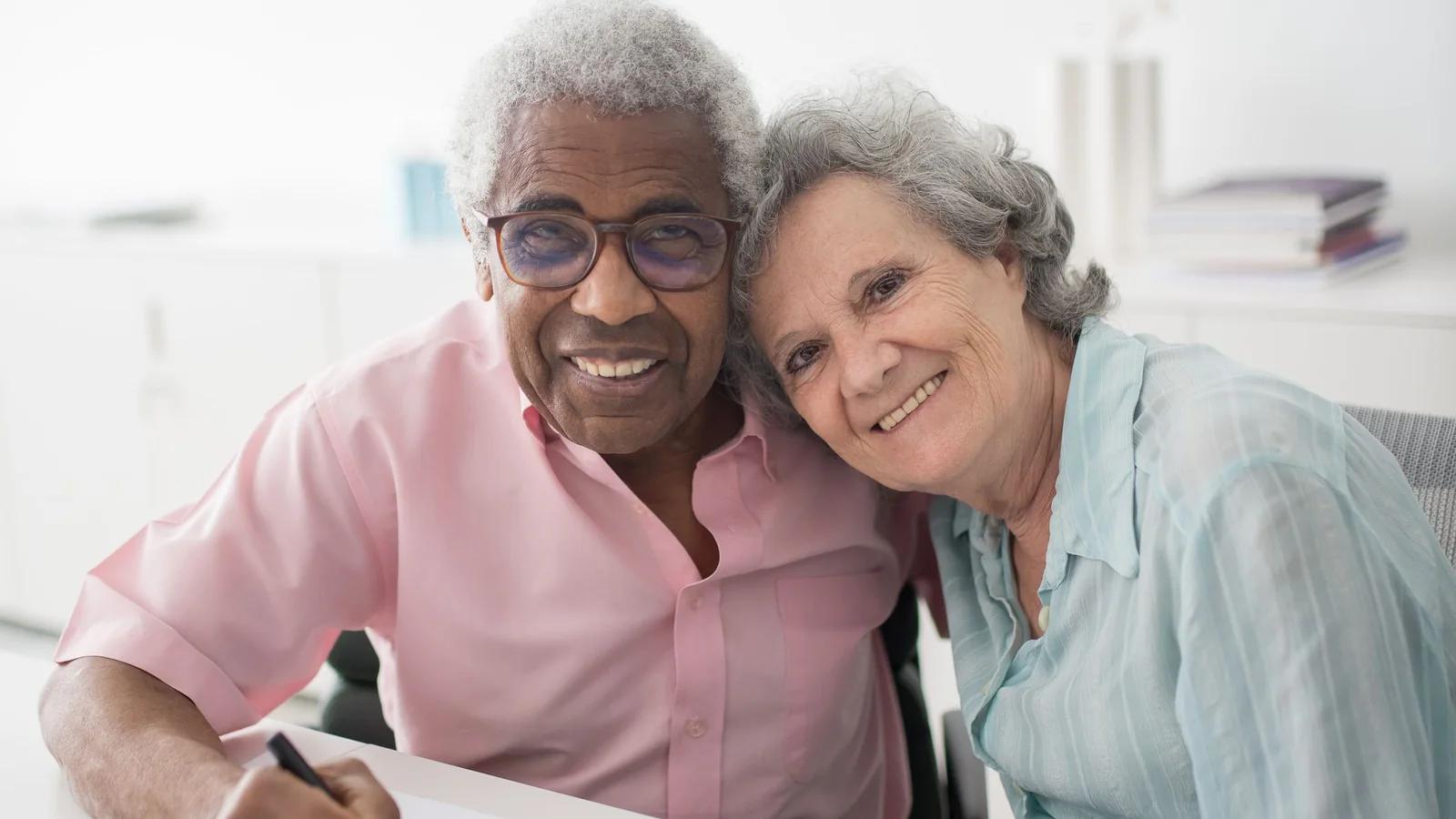 Un couple âgé signe des documents de succession à une table
