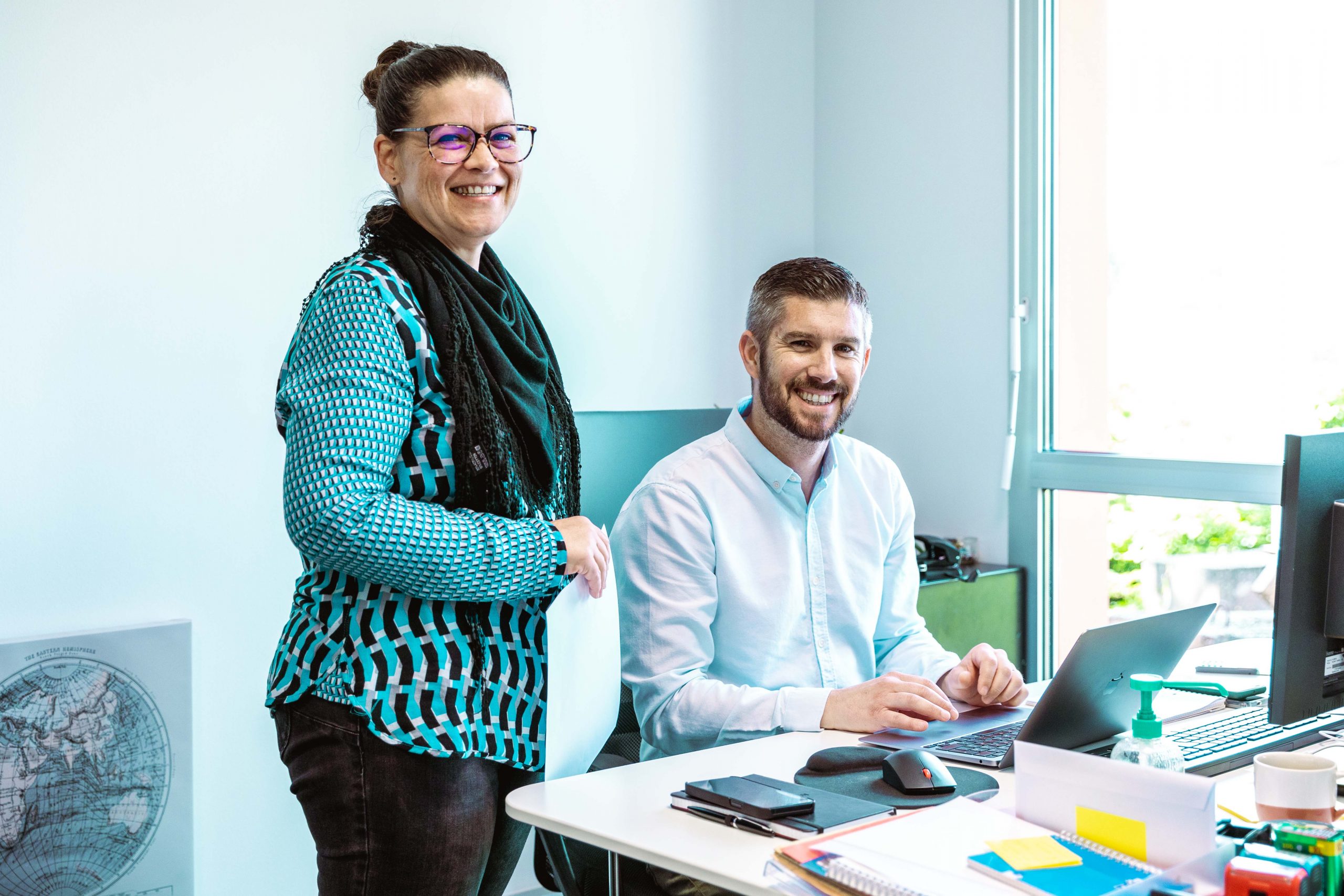 Deux personnes devant un bureau qui sourient à l'objectif